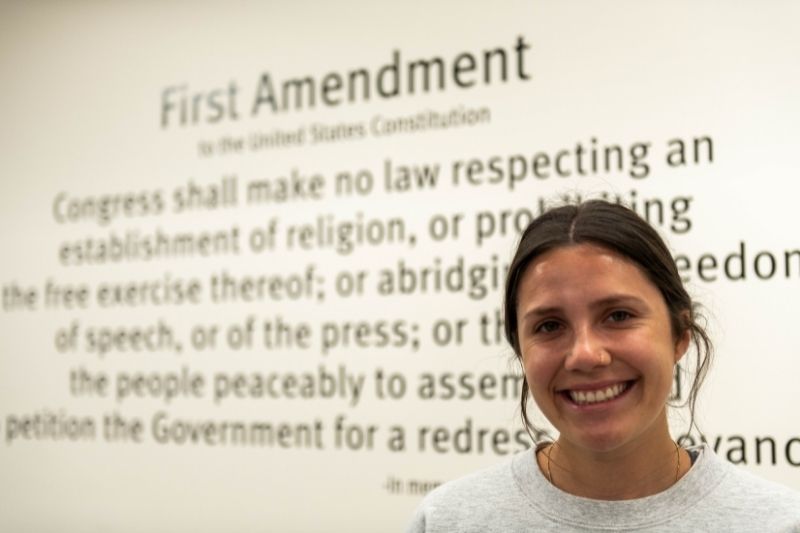 First Amendment quote on wall behind a smiling student